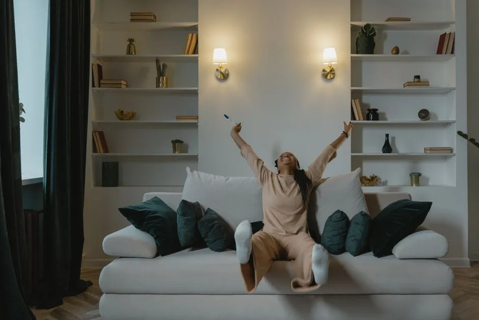 A joyful expectant mother celebrates a positive pregnancy test result while sitting on a sofa indoors.
