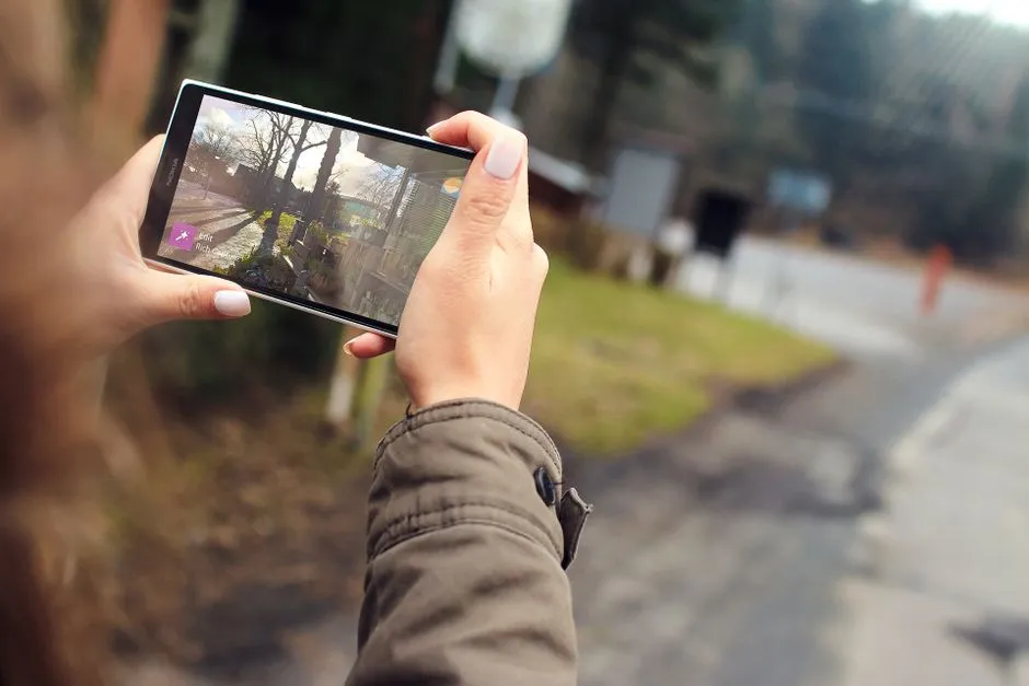 Woman capturing outdoor scenery using a smartphone. Close-up of hands holding the device.