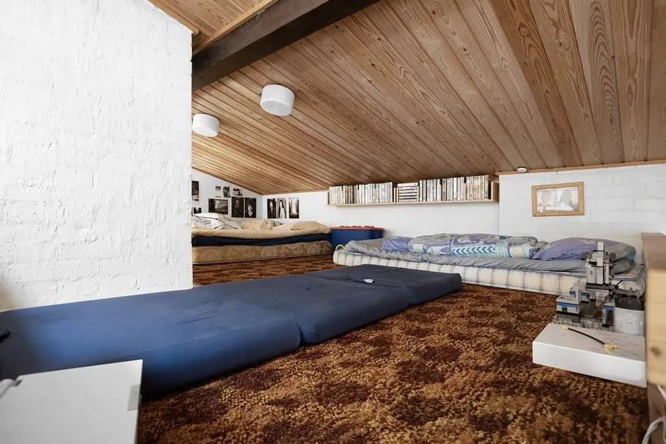 Charming attic room featuring wooden ceilings, mattresses, and warm decor. Ideal for cozy living space inspiration.