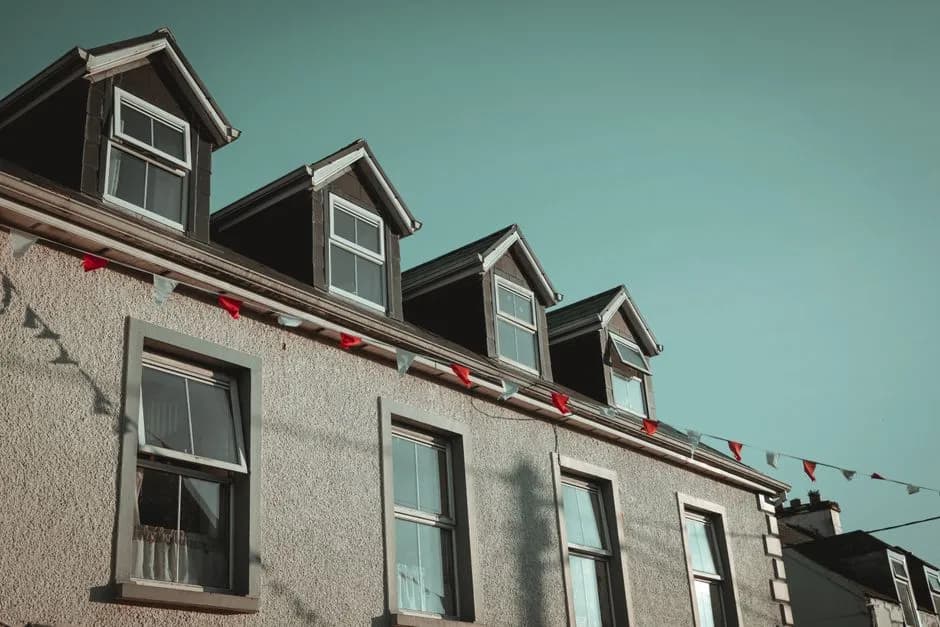 Quaint residential building with dormer windows and decorative bunting under clear skies.