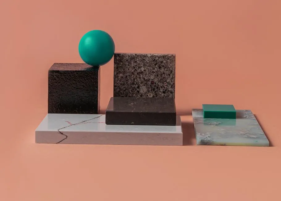 A minimalist geometric arrangement with various textured blocks and a sphere on a peach backdrop.