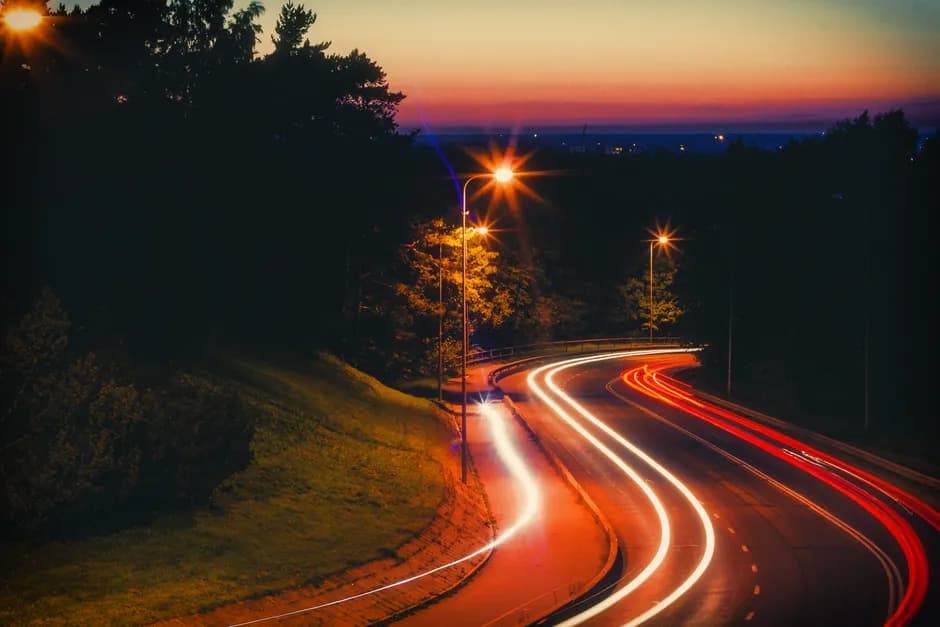 Long exposure capturing light trails on a road at sunset, creating a dramatic urban scene.