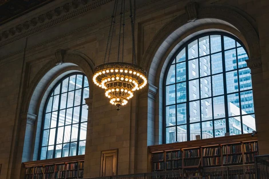 View of the chandelier and arched windows inside the New York Public Library, showcasing classic architecture.