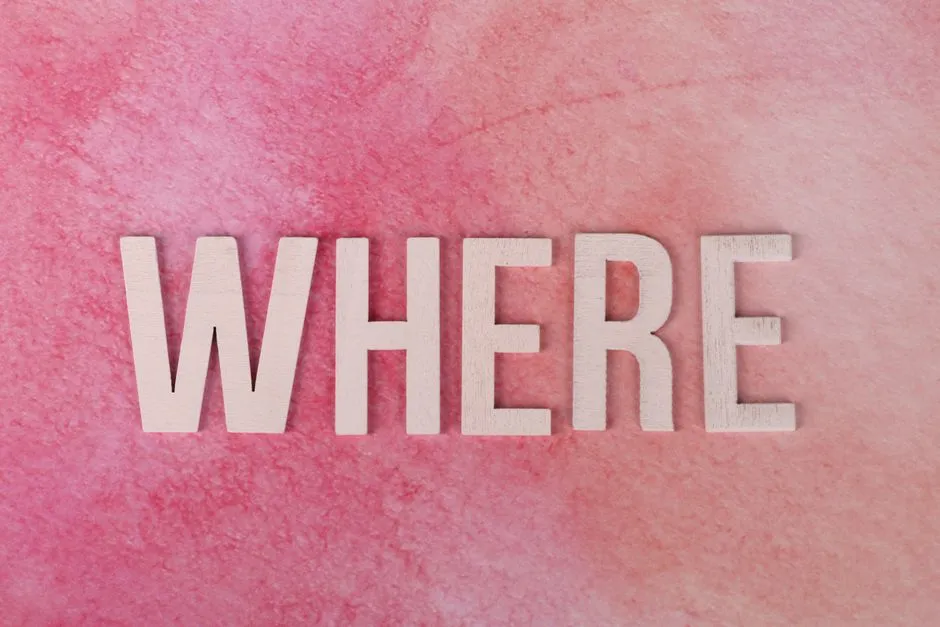 The word WHERE in bold wooden letters on a vibrant pink textured background, offering copyspace.