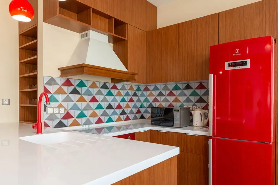 Contemporary kitchen design featuring colorful geometric tiles and red appliances.