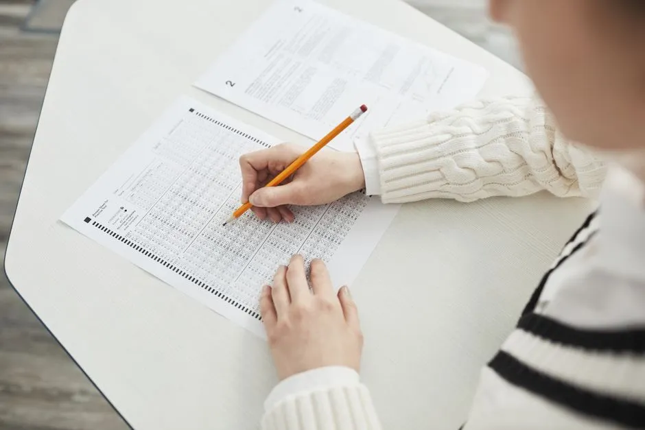 Close-up of a student filling out a multiple-choice exam in a quiet classroom setting.