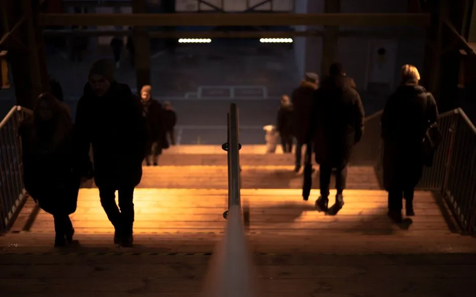 People walking up and down illuminated urban stairs in a moody evening setting.