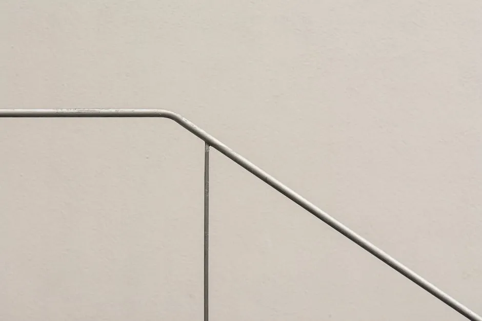 A simple and elegant minimalist image of a steel railing against a textured wall.