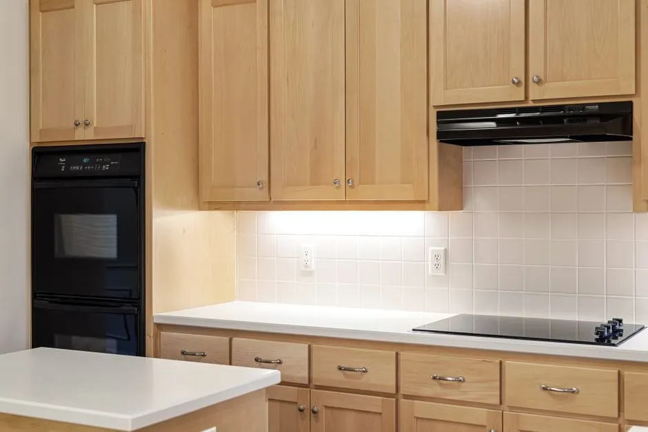 Sleek kitchen featuring wooden cabinets, black oven, and induction stove.