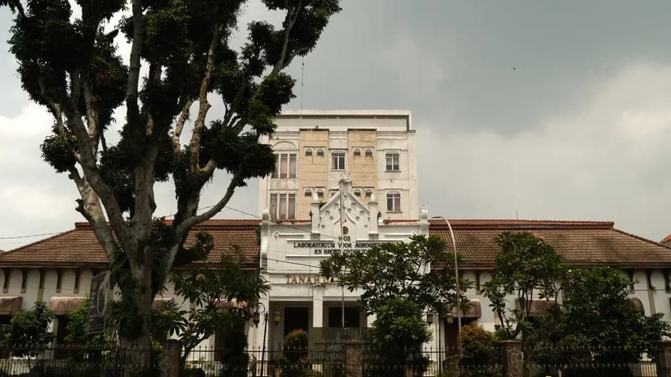 Outdoor view of a historic laboratory building surrounded by lush trees, under a cloudy sky.