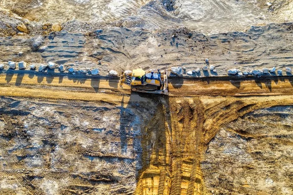 Aerial shot of bulldozer in action at a sandy construction site.