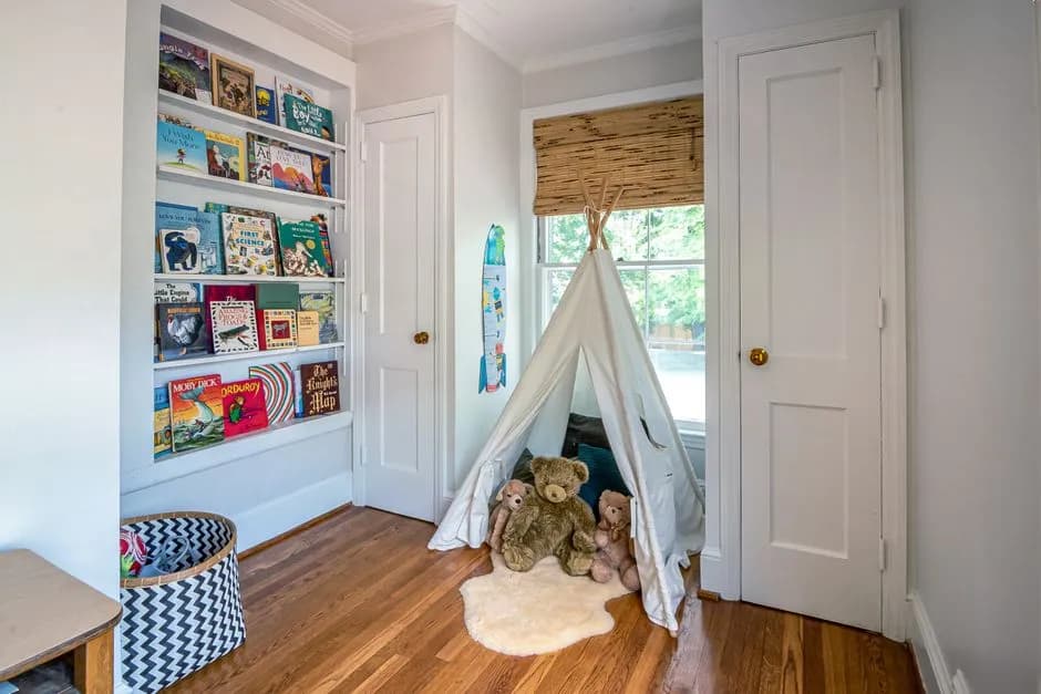 Charming children's room featuring a play tent, stuffed toys, and a bookshelf filled with colorful books.