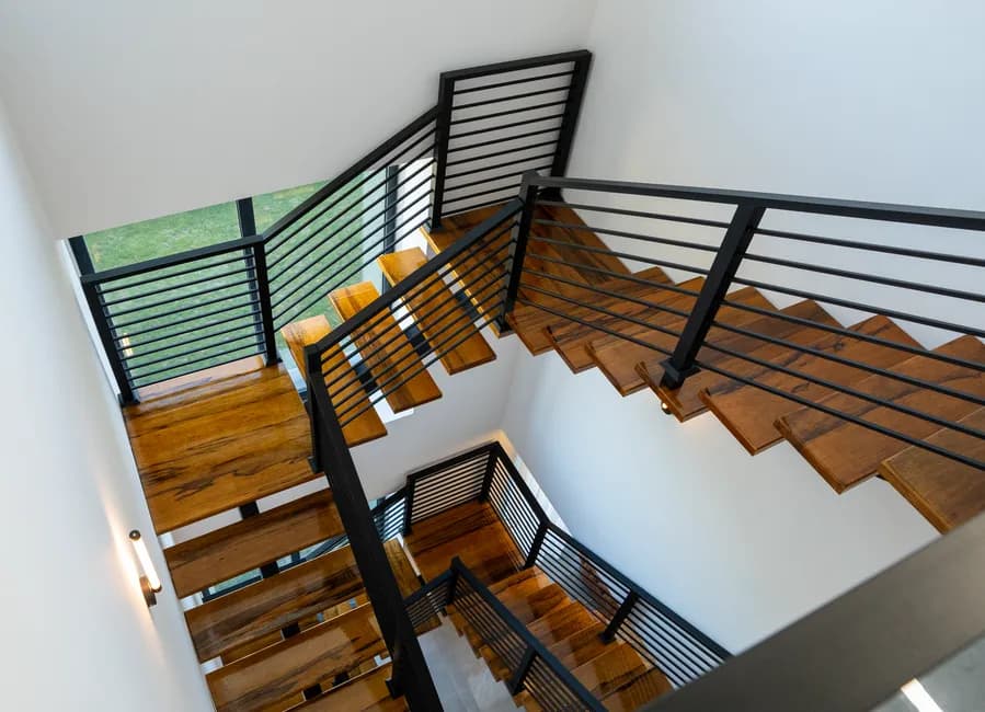 High-angle view of a contemporary wooden staircase with metal railings in a bright interior.
