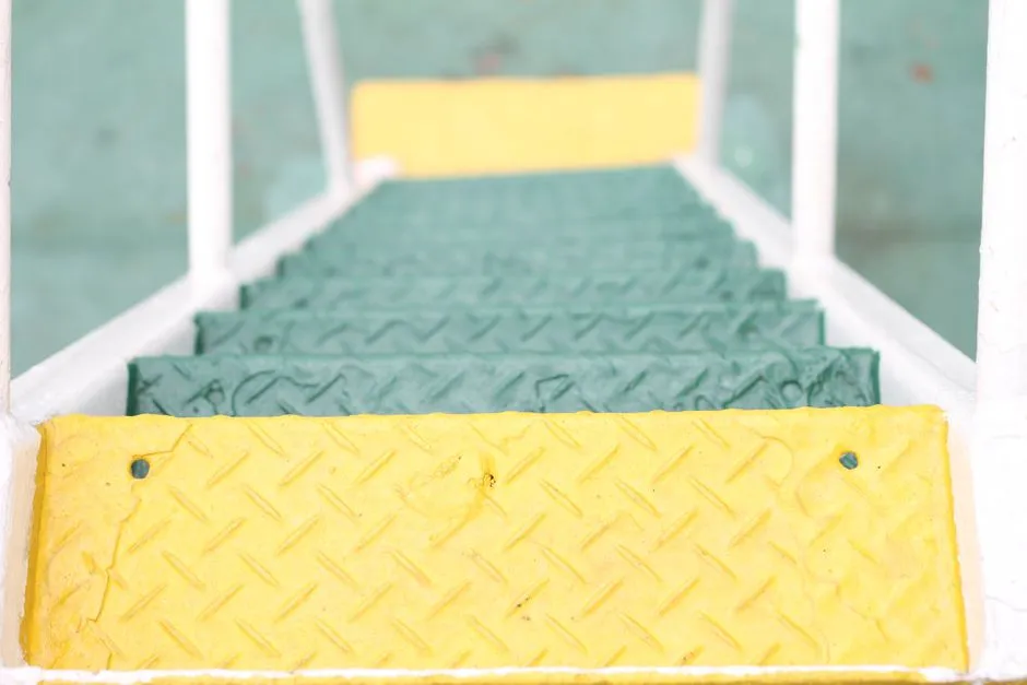 Close-up of vibrant yellow and green metal stairs with diamond pattern design for outdoor architecture.