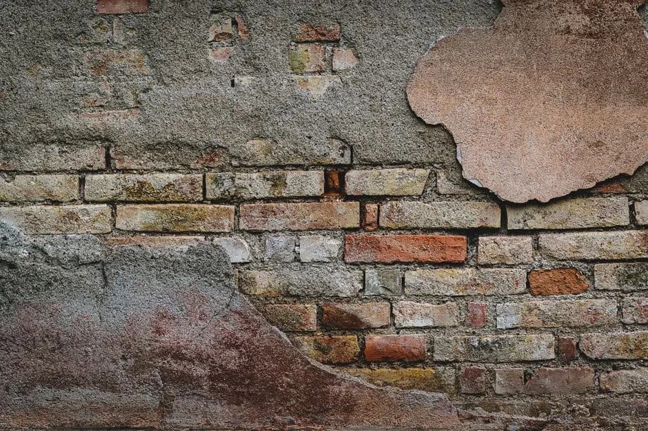 Close-up of a rustic brick wall showing aged plaster and textures. Ideal for backgrounds.
