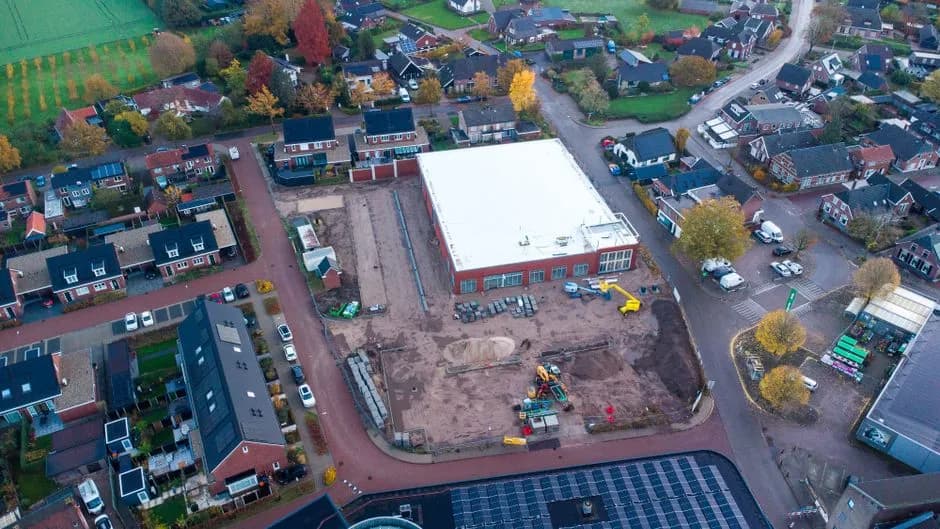 Aerial shot of a construction site amidst residential homes in autumn, Netherlands.
