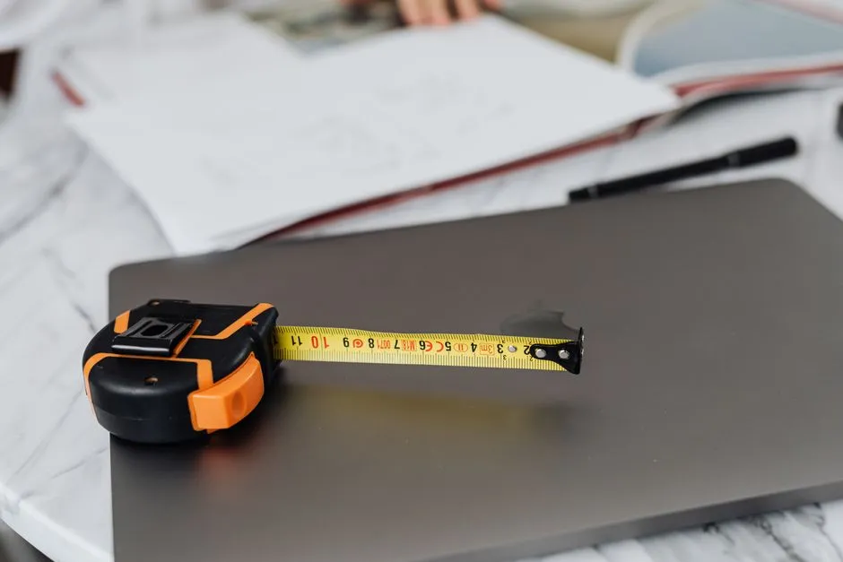 Close-up image of a measuring tape and a laptop on a work desk, representing precision in work.