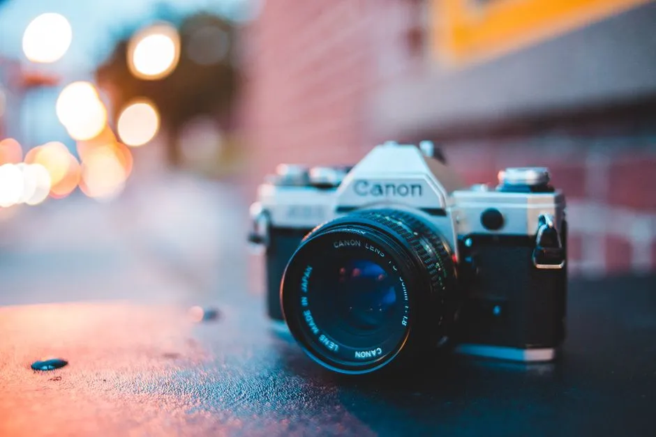 Ground level of vintage photo camera on sidewalk with water drops near urban building in twilight