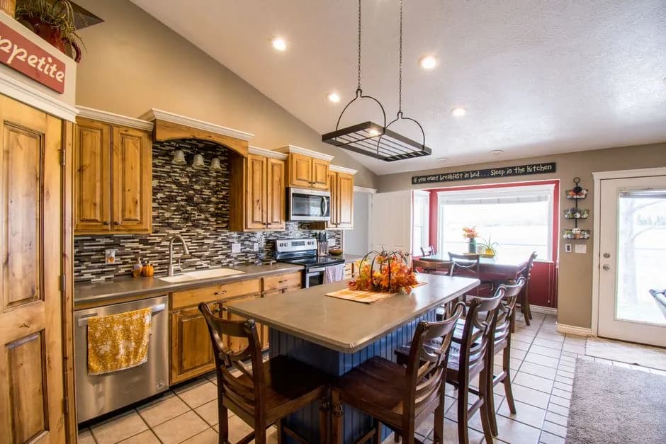 Bright rustic kitchen interior featuring wooden cabinets and a central island with high stools.
