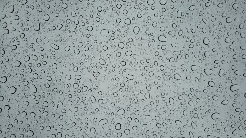 Detailed macro image capturing various water droplets on a glass surface, showcasing texture.