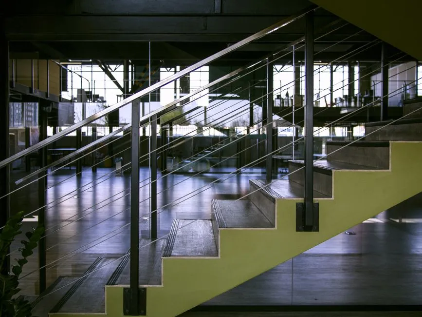 Spacious interior featuring modern staircase with glass railings and metal design elements.