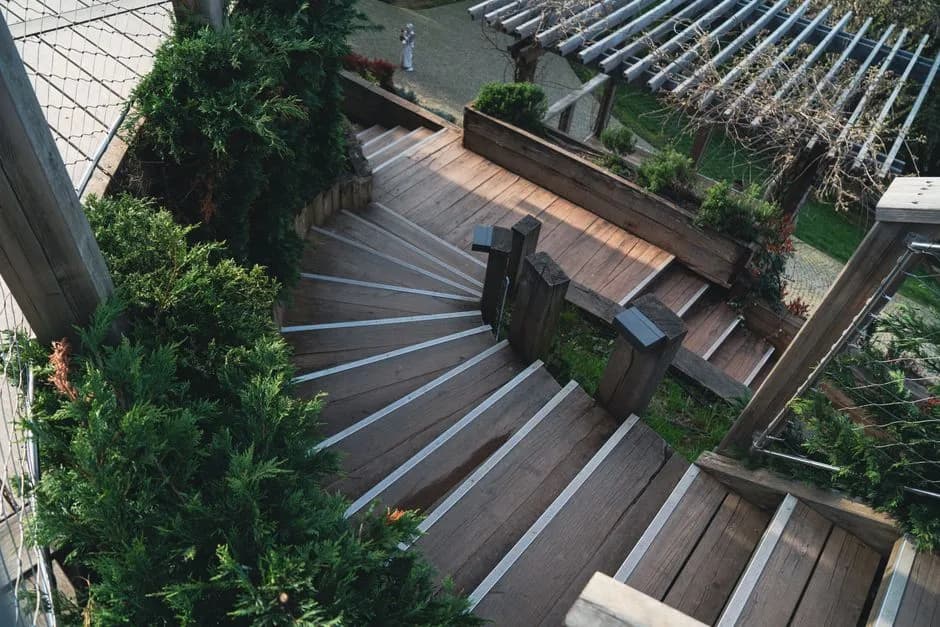 Explore the elegance of a wooden staircase surrounded by lush greenery in an outdoor garden.