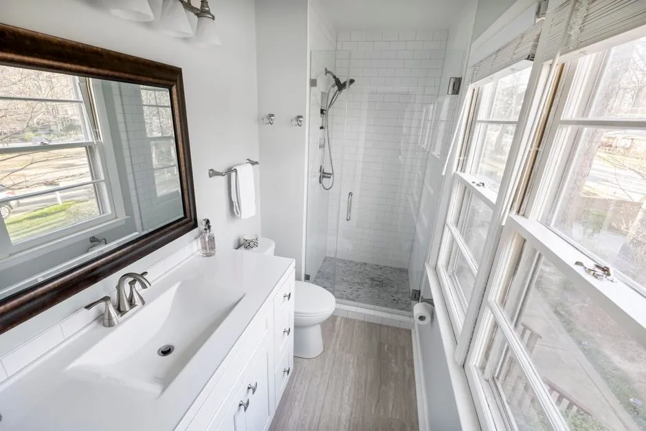 Contemporary minimalist bathroom featuring a tiled shower, vanity, and ample natural light.