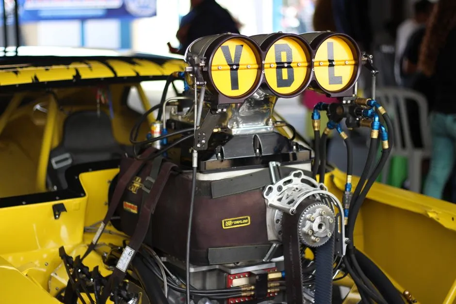 Close-up of a high-performance car engine labeled YBL in a yellow vehicle. Captured indoors.