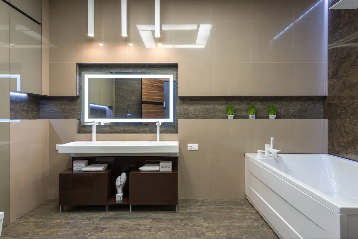 Finished light bathroom with white tub, vanity and lit mirror