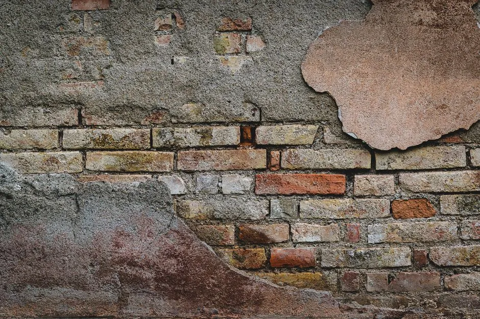 Close-up of a rustic brick wall showing aged plaster and textures. Ideal for backgrounds.