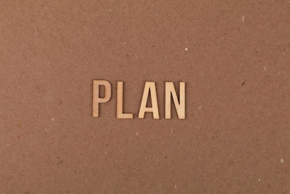 Wooden letters spelling 'PLAN' on a textured cardboard background with ample copy space.