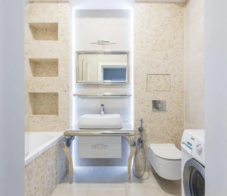Modern bathroom interior with mirror and washstand between washing machine and bathtub in light house